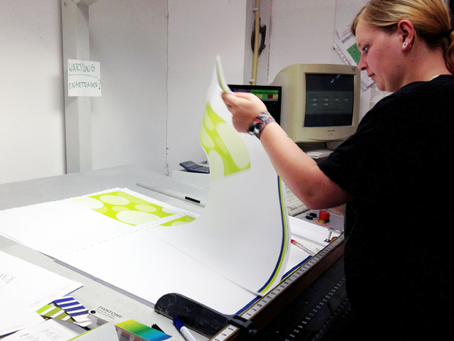 Press technician examining proofs at work table.