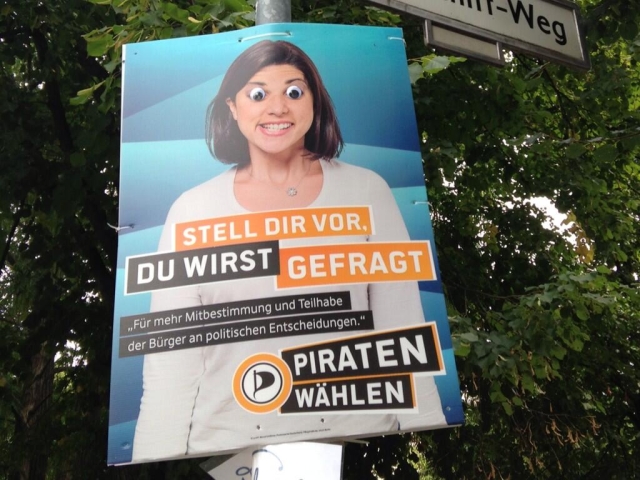 Campaign poster with photo of a woman, with googly eyes stuck on the poster over the eyes.