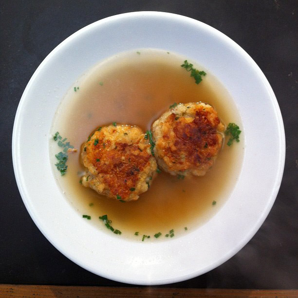 Bowl of beef broth with two bread-and-cheese dumplings