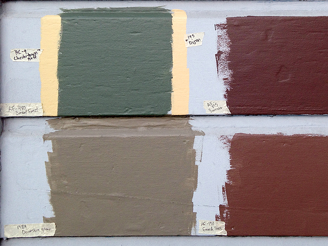 Four patches of different-colored paint on a wall, labeled with hand-written masking tape labels