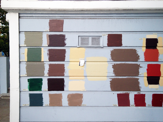 Many different-colored patches of paint on the side of a house