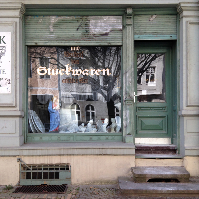 Old green storefront with window lettering in blackletter