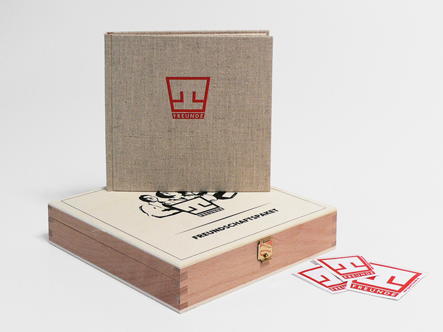 Small square book, with "T" logo, standing on its wooden box