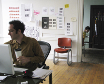 Man at desk next to cluttered bulletin board